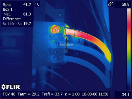 Thermal image of an electrical connection with measurement overlay. A single conductor and its termination glow white and red against cool blue surrounding gear, with on-screen readings of spot 41.7 degrees Celsius, box maximum 61.3 degrees, and a difference of 19.7 degrees.