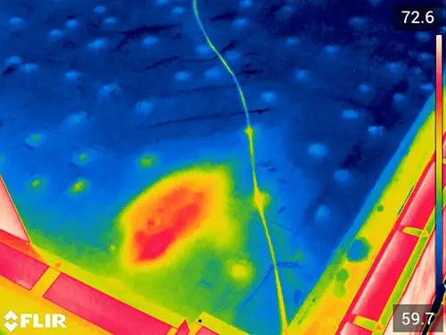 Thermal image of a membrane roof at night, scale 59.7 to 72.6 degrees. A defined red and yellow plume of retained heat sits in the middle of an otherwise cool blue roof field, indicating saturated insulation beneath the membrane.